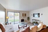 Located at 517 E Edgewood Blvd in Lansing, Michigan, this one-bedroom, one-bathroom unit is thoughtfully laid out across a single floor. The living room serves as the centerpiece of the home, featuring a classic brick fireplace, carpet flooring, and a large sliding glass door fitted with vertical blinds that floods the space with natural light and provides a view of the surrounding greenery. An accent wall in muted olive adds a touch of color contrast to the bright, neutral palette. The dining area flows naturally from the living room, offering a functional space for everyday meals. The kitchen is galley-style with white cabinetry, ample counter space, a built-in sink, and white appliances including a range and refrigerator, all beneath a textured ceiling. The bedroom is a comfortable retreat highlighted by a bold red accent wall, plush carpet, a window with natural light, and a dedicated closet. The bathroom features a clean, white tub-shower combination. Additional utility and hallway spaces contribute to the overall practicality of this well-organized home, which also includes an unclassified room offering flexible usage potential.