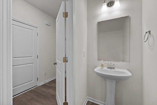 Powder-bathroom with a sleek pedestal sink, mirror, and white walls - 2863 Aubrey St