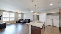 Located at 801 W 4th Ave in Stillwater, Oklahoma, this well-appointed 2-bedroom, 2-bathroom unit offers a thoughtfully designed single-level layout. The open-concept kitchen and living area serves as the heart of the home, where rich dark-cabinetry kitchen pairs with granite countertops, stainless steel appliances, and a large center island with bar seating and pendant lighting overhead. The living room features wood-style plank flooring, a ceiling fan, and multiple windows that allow natural light to fill the space. Both bedrooms are carpeted and equipped with ceiling fans. The primary bedroom offers a generous footprint with access to its own bathroom, while the second bedroom includes a window with natural light. Each bathroom is finished with wood-style flooring, a tub-shower combination, and clean, neutral tones. The second bathroom also features dark wood vanity cabinetry with a white countertop. A dedicated in-unit laundry area houses a full-size washer and dryer. Throughout the unit, neutral wall tones and consistent finishes create a cohesive and practical living environment.