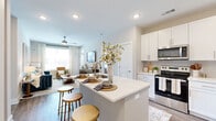 This thoughtfully designed 2-bedroom, 2-bathroom residence on a single level offers a seamless open-concept layout that connects the kitchen, dining area, and living room into one cohesive living space. The kitchen is a standout feature, showcasing white shaker cabinetry, a light quartz countertop, a center island with an undermount sink and bar seating, and a full suite of stainless steel appliances including a refrigerator with ice maker, range, microwave, and dishwasher. A washer and dryer closet is conveniently tucked nearby. The living room is bright and inviting, with large windows that flood the space with natural light and a ceiling fan overhead. Wood-look flooring runs throughout the main living areas, adding warmth and continuity. The primary bedroom features a large window with outdoor views and access to a private en suite bathroom with a walk-in glass shower, single vanity, and light tile flooring. The second bedroom is equally well-lit with its own closet and access to a full bathroom complete with a soaking tub and shower combination. Two closets provide ample storage throughout. A private balcony extends the living space outdoors, rounding out this refined and functional residence.