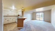 This single-floor residence at 22492 Stillwater Ct in Elkhart, Indiana, offers a straightforward and functional layout designed for comfortable everyday living. The open-concept living and dining area is generously proportioned, finished with wall-to-wall carpeting that adds warmth underfoot. A large sliding glass door at the far end of the living space fills the room with natural light and provides direct access to an outdoor balcony, offering views of the surrounding greenery.

The kitchen connects seamlessly to the living area via a peninsula counter with an overhanging breakfast bar, ideal for casual dining. The kitchen is equipped with white cabinetry featuring wood-toned hardware, a gas range with an overhead exhaust, a dishwasher, a refrigerator, and a sink. Tile flooring in a neutral stone pattern runs throughout the kitchen, providing a durable and easy-to-clean surface.

The bedroom is a calm, carpeted space with neutral walls and a window fitted with blinds that allows natural light while maintaining privacy. Closet storage is available, as evidenced by the bifold closet doors visible in the hallway area.

The bathroom features tile flooring consistent with the kitchen, a vanity with storage cabinetry, and a separate shower enclosure. Overall, the space presents a clean, neutral palette throughout.