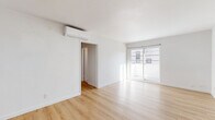 Located at 114 S Gramercy Pl in the heart of Los Angeles' Koreatown, this 2-bedroom, 2-bathroom unit offers a clean, modern aesthetic throughout its efficiently designed single-floor layout. Light wood laminate flooring runs continuously across the living room, hallway, and both bedrooms, creating a bright and cohesive feel.

The living room is a well-proportioned open space featuring crisp white walls, a wall-mounted mini-split AC unit, and a sliding glass door that invites ample natural light while providing outdoor access. The kitchen stands out with retro-inspired mint-green cabinetry accented by gold hardware, light countertops, and a white gas range, offering a charming contrast to the otherwise contemporary interior.

Both bedrooms are finished in the same light-toned flooring and white walls. Each room is equipped with a wall-to-wall sliding panel closet for generous storage, and windows that bring in natural light. The primary bedroom also features its own wall-mounted AC unit.

The two bathrooms are finished in white tile. One includes a tiled shower stall with matte black fixtures, while the other features a full bathtub/shower combo with white subway tile surround, matte black hardware, and a window above for ventilation and light. A hallway connects all rooms, completing this well-laid-out unit.