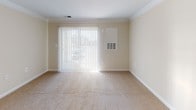 Located at 14431 Traville Garden Cir, Apt 214 in Rockville, Maryland, this single-floor apartment offers a functional and comfortable layout with well-defined living spaces. The kitchen is equipped with warm oak cabinetry providing ample storage, white appliances including a dishwasher, range, and refrigerator, and a double-basin sink. Light hardwood-style flooring anchors the kitchen area, which flows seamlessly into the carpeted living and dining space. Crown molding adds a refined touch to the living area, which benefits from natural light streaming through a large sliding glass door dressed with vertical blinds, opening to an outdoor view. The bedroom features neutral beige carpeting, soft-toned walls, and a window with blinds that allows natural light to brighten the room. The bathroom is appointed with a wood-toned vanity, a wide mirror, a single-basin sink with chrome fixtures, a toilet, and a walk-in shower with a curtain rod. Throughout the unit, neutral wall colors and consistent finishes create a clean, cohesive aesthetic. The overall ambiance is practical and move-in ready, well-suited for comfortable everyday living in a residential Rockville community.