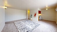Located at 1033 N Downing St in Denver's vibrant Capitol Hill neighborhood, this one-bedroom, one-bathroom unit offers a thoughtfully arranged single-floor layout. The open living room is generously proportioned, featuring wall-to-wall carpet, neutral white walls, a wall sconce, and a classic wood-paneled entry door. A baseboard heating unit runs along the perimeter, ensuring warmth throughout the space. Natural light filters in through a large picture window in the bedroom, offering pleasant views of mature trees and the surrounding neighborhood streetscape. The galley-style kitchen is efficiently designed, lined with warm wood cabinetry on both sides, track lighting overhead, a single-basin sink, a white electric range, and a dedicated walk-in pantry for ample storage. The tile flooring in the kitchen adds a practical contrast to the carpeted living areas. The bathroom features a tiled tub-and-shower combination enclosed with glass sliding doors. The spacious primary bedroom is quiet and well-lit, providing a comfortable retreat. Overall, the unit presents a clean, functional layout well-suited for everyday living in one of Denver's most walkable and established neighborhoods.