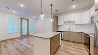 Located at 11575 W Roosevelt St in Avondale, Arizona, this well-appointed one-bedroom, one-bathroom residence offers a thoughtfully designed single-floor layout with a clean, contemporary aesthetic. The open-concept kitchen and living area serves as the heart of the home, showcasing a large central island topped with granite countertops and illuminated by two striking globe pendant lights. The kitchen is outfitted with stainless steel appliances — including a French door refrigerator with ice maker, electric range, built-in microwave, and dishwasher — complemented by two-tone cabinetry in white and warm wood tones, a subway tile backsplash, and a undermount sink. Light wood-style flooring flows throughout the main living areas, adding warmth and continuity. The living area benefits from natural light via a glass door that opens to the exterior. The spacious bedroom features plush carpet and a large window with blinds, creating a comfortable retreat. A walk-in closet with dual clothing rods and shelving provides generous storage. The bathroom is finished with a wide granite-topped vanity, wood-tone cabinetry, a full tub-shower combo with tile surround, and matching wood-style flooring. A carpeted hallway connects the private areas of the home seamlessly.