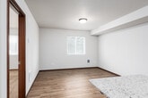 This single-floor residence offers a thoughtfully designed layout that balances functionality and comfort. The interior is unified by warm hardwood-style flooring that flows through the main living and kitchen areas, complemented by rich dark wood trim and door frames throughout.

The kitchen serves as the centerpiece of the home, featuring rich dark wood cabinetry, granite countertops, and a full suite of stainless steel appliances including a refrigerator, range, microwave, and dishwasher. A central island with matching granite provides additional workspace and a natural gathering point. The kitchen opens seamlessly toward the living area, creating an open-concept feel that encourages easy movement throughout the space.

A hallway connects the main living area to the private rooms, offering access to a well-sized bedroom outfitted with plush carpeting and a window that brings in natural light and outdoor views. The bathroom is finished with a granite-topped vanity with dark wood cabinetry, a tile accent backsplash, and a large mirror. Notably, a stacked washer and dryer unit is conveniently integrated into the bathroom area, providing in-unit laundry without requiring a separate dedicated room.

Overall, the space presents a clean, modern aesthetic with consistent finishes, practical storage solutions, and a cohesive design that makes efficient use of the single-floor footprint.
