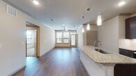 This single-floor residence offers a thoughtfully designed open-concept layout that seamlessly connects the kitchen and living area. The kitchen is a standout feature, showcasing rich dark cabinetry, granite countertops, a central island with an undermount sink, stainless steel appliances, and elegant pendant lighting — all set atop durable hardwood-style flooring. Crown molding adds a refined touch to the living area, which is bathed in natural light from multiple windows and features a ceiling fan for added comfort.

The bedrooms are carpeted for warmth and comfort, each equipped with a ceiling fan and windows offering outdoor views of lush greenery. The primary bedroom connects to a well-appointed en-suite bathroom featuring a double vanity with granite countertops, dark cabinetry, hardwood-style flooring, and a separate shower. A generously sized walk-in closet with built-in shelving and hanging rods provides ample storage. A second full bathroom includes a tiled tub-shower combination and granite vanity countertop. The neutral color palette and consistent finishes throughout create a cohesive, modern ambiance across the entire space.