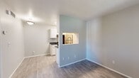 Located at 651 S Bunbury Cove in Salt Lake City, Utah, this single-floor unit offers a well-organized layout designed for comfortable everyday living. The galley-style kitchen is a functional highlight, featuring white shaker cabinets, dark countertops, a stainless steel sink with a modern faucet, and black appliances including an electric range and refrigerator. A pass-through window connects the kitchen to the adjacent living and dining area, creating an open, communicative flow between spaces. The living area is finished with wood-look luxury vinyl plank flooring in a warm gray tone, which continues into the entryway and secondary room. Natural light filters through blinds-equipped windows, contributing to the bright and neutral ambiance found throughout the unit. A dedicated bedroom features plush carpet flooring and a window that further enhances the sense of light and openness. The entryway provides a clean transition into the unit, with its own window and direct access door. Neutral gray and beige wall tones are carried consistently across all rooms, lending the space a cohesive and move-in-ready aesthetic. The layout balances practicality with livability, making it a well-appointed option in the Salt Lake City area.
