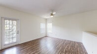 Located at 5101 SW 60th St in Ocala, Florida, this two-story residence offers a well-organized layout designed for comfortable everyday living. The main living area on the first floor features rich wood-look flooring that extends throughout, complemented by neutral white walls and a ceiling fan with light fixture. Large windows dressed with vertical blinds allow natural light to fill the space, while a glass-paned exterior door provides access to the outdoors. An open loft-style view from the upper level overlooks the main floor, adding architectural depth to the interior.

The kitchen is equipped with white cabinetry, light granite-style countertops, and black appliances including a refrigerator, electric coil range, and over-the-range microwave, all set over the same wood-look flooring.

The bedrooms are carpeted in warm neutral tones and feature ceiling fans, windows with views of surrounding greenery, and generous wall space. The bathroom is finished with light ceramic tile flooring, a tub-shower combination with white tile surround, and clean, simple fixtures.

A staircase connects the two floors, and the overall aesthetic throughout is clean and bright, with a consistent neutral palette that creates a versatile, move-in-ready environment.