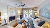 Located at 100 Granby Crossing in Cayce, South Carolina, this well-appointed 2-bedroom, 2-bathroom residence offers a comfortable and cohesive single-floor layout. The living room serves as the heart of the home, featuring a tiled fireplace, ceiling fan, and sliding glass doors that open to a private balcony with outdoor views — filling the space with natural light. The adjoining dining area makes an impression with a bold terracotta accent wall and easy access to additional storage. The galley-style kitchen is outfitted with granite countertops, white cabinetry, and a full suite of stainless steel appliances, including a range, microwave, dishwasher, and refrigerator, all set over wood-look flooring. The primary bedroom is generously sized, featuring plush carpeting, a ceiling fan, large windows, and a dedicated closet. The second bedroom mirrors this comfort with its own ceiling fan and ample natural light. Both bathrooms are finished with tiled tub-shower combinations and wood-look flooring, offering a clean and functional design. Two closets throughout the residence provide practical storage solutions. The overall palette of warm neutrals and soft tones creates a welcoming ambiance throughout the home.