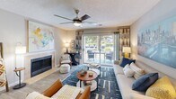 Located at 100 Granby Crossing in Cayce, South Carolina, this well-appointed 2-bedroom, 2-bathroom residence offers a comfortable and cohesive single-floor layout. The living room serves as the heart of the home, featuring a tiled fireplace, ceiling fan, and sliding glass doors that open to a private balcony with outdoor views — filling the space with natural light. The adjoining dining area makes an impression with a bold terracotta accent wall and easy access to additional storage. The galley-style kitchen is outfitted with granite countertops, white cabinetry, and a full suite of stainless steel appliances, including a range, microwave, dishwasher, and refrigerator, all set over wood-look flooring. The primary bedroom is generously sized, featuring plush carpeting, a ceiling fan, large windows, and a dedicated closet. The second bedroom mirrors this comfort with its own ceiling fan and ample natural light. Both bathrooms are finished with tiled tub-shower combinations and wood-look flooring, offering a clean and functional design. Two closets throughout the residence provide practical storage solutions. The overall palette of warm neutrals and soft tones creates a welcoming ambiance throughout the home.