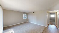 Located at 6131 North 16th Street in Phoenix, Arizona, this single-floor, 2-bedroom, 2-bathroom home offers a well-organized layout that maximizes functionality and comfort. The living room is bright and open, featuring plush carpeting, neutral-toned walls, and multiple windows including a sliding glass door that fills the space with natural light. The kitchen stands out with its modern design, showcasing dark wood cabinetry, white quartz countertops, a classic subway tile backsplash, and a full suite of stainless steel appliances including a range, microwave, refrigerator, and dishwasher. Light wood-style flooring and a window add to the kitchen's clean, contemporary feel. Both bedrooms are carpeted and offer a calm, neutral palette with ample natural light from well-placed windows. The primary bedroom includes a spacious built-in closet with sliding doors. Each bathroom is cleanly finished — one features a modern vanity with dark cabinetry, white countertop, and a tub/shower combo, reflecting the same updated aesthetic found throughout the home. A hallway connects the spaces efficiently, and in-unit laundry hookups are visible in the floor plan, adding practical convenience to this well-appointed Phoenix residence.
