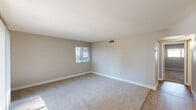 Located at 6131 North 16th Street in Phoenix, Arizona, this single-floor, 2-bedroom, 2-bathroom home offers a well-organized layout that maximizes functionality and comfort. The living room is bright and open, featuring plush carpeting, neutral-toned walls, and multiple windows including a sliding glass door that fills the space with natural light. The kitchen stands out with its modern design, showcasing dark wood cabinetry, white quartz countertops, a classic subway tile backsplash, and a full suite of stainless steel appliances including a range, microwave, refrigerator, and dishwasher. Light wood-style flooring and a window add to the kitchen's clean, contemporary feel. Both bedrooms are carpeted and offer a calm, neutral palette with ample natural light from well-placed windows. The primary bedroom includes a spacious built-in closet with sliding doors. Each bathroom is cleanly finished — one features a modern vanity with dark cabinetry, white countertop, and a tub/shower combo, reflecting the same updated aesthetic found throughout the home. A hallway connects the spaces efficiently, and in-unit laundry hookups are visible in the floor plan, adding practical convenience to this well-appointed Phoenix residence.