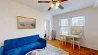 Located in Chicago's prestigious Gold Coast neighborhood, this 1-bedroom, 2-bathroom residence offers a thoughtfully designed layout that maximizes every inch of its compact footprint. The living area welcomes you with warm parquet hardwood flooring, crisp white walls, and a ceiling fan that adds both function and charm. A vibrant blue sofa anchors the living space, which flows seamlessly into a well-equipped kitchen featuring gray shaker-style cabinetry, stainless steel appliances, an in-unit washer, and recessed lighting — providing everything needed for comfortable city living. Natural light filters through blinds on multiple windows, brightening the space throughout the day. The bedroom continues the parquet flooring theme and includes a ceiling fan, windows with city views, and direct access to one of the two bathrooms. The primary bathroom is elegantly finished with marble-style tile flooring, a wood-toned vanity with a crisp white countertop, a gold-framed mirror, and a glass-enclosed shower, lending a refined, spa-like feel. A second bathroom provides added convenience. Colorful artwork displayed throughout the residence adds personality and warmth. Situated steps from Chicago's lakefront, dining, and entertainment, this residence combines classic architectural character with modern updates.