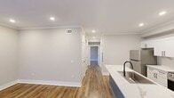 This 870-square-foot, single-story unit offers 3 bedrooms and 2 bathrooms with a clean, modern aesthetic throughout. The open-concept kitchen and living area serves as the heart of the home, showcasing white shaker cabinets, quartz countertops with a marble-inspired finish, a bold blue shiplap kitchen island with a built-in sink, stainless steel appliances, and recessed lighting with crown molding. Hardwood-style luxury vinyl plank flooring runs consistently throughout the entire unit, adding warmth and continuity. The primary bedroom measures 170 square feet and includes a walk-in closet and natural light from dual windows. The additional bedrooms are well-proportioned with neutral gray walls, white trim, and ample outlets. The primary bathroom features a dual-sink vanity with white shaker cabinetry, a central linen tower, matte black hardware, and large mirrors. The second bathroom is appointed with matching finishes, including wood-look flooring, white cabinetry, and matte black fixtures. Each room benefits from natural light via blinds-fitted windows, and the unit includes an exterior door with window access from the living area.