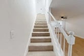 Located at 2220 NW 55th Blvd in Gainesville, FL, this two-bedroom, two-bathroom two-story home offers a well-organized layout spread across two floors. The ground level features an open-concept combined living and dining area with light wood-style flooring, a ceiling fan, and a white-railed staircase that leads to the upper level. The kitchen is outfitted with white shaker cabinets, light quartz countertops, a stainless steel appliance suite including a refrigerator, range, microwave, and dishwasher, plus a pantry closet with louvered doors. A dedicated laundry area and a full bathroom are also found on this floor. Upstairs, the two bedrooms each feature light wood flooring and ceiling fans. The primary bedroom is generously sized with a closet and sliding glass doors opening onto a private balcony with wooded views. The second bedroom offers a ceiling fan and a bright window. A full bathroom with a tub-shower combination and wood-style flooring serves the upper level. Throughout the home, crisp white walls, multiple closets, and consistent flooring create a clean, cohesive aesthetic that is both functional and inviting.