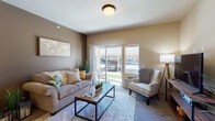 Located at 15720 East 4th Avenue in Spokane Valley, Washington, this well-appointed single-floor unit offers a thoughtfully designed layout with distinct functional areas that flow seamlessly together. The kitchen is a standout feature, designed in a galley style with rich dark wood cabinetry, granite countertops, tile backsplash, hardwood-style flooring, and black appliances. A pass-through breakfast bar with bar seating connects the kitchen to the living area, and a dedicated pantry provides generous additional storage. Adjacent to the kitchen, a cozy dining nook is finished with hardwood-style flooring and illuminated by a classic chandelier overhead, making it an ideal spot for everyday meals. The living room is carpeted and bathed in natural light from large sliding glass doors that open directly to an outdoor patio, offering views of the surrounding community. Warm taupe walls and plush carpet create a comfortable, inviting atmosphere. The bedroom is a quiet, spacious retreat with neutral tones and soft carpeting throughout. The full bathroom features hardwood-style flooring, a granite-topped vanity with rich wood cabinetry, and a tub-shower combination. A versatile secondary room, ideal as a home office or flex space, includes carpeting and a bright window with natural light. This unit combines functional design with warm, cohesive finishes throughout.