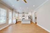 Located at 3110 Doe River Way in Matthews, NC, this two-story home offers a well-organized layout spread across two floors. The exterior features classic lap siding in a neutral gray tone, a concrete driveway, and landscaped grounds with a manicured lawn. The main level houses the open-concept kitchen and living area, where light hardwood flooring flows throughout. The kitchen is a standout, featuring white shaker cabinetry with glass-front upper cabinets, a large center island with a white quartz countertop, stainless steel appliances including a gas range and French door refrigerator, a stainless steel hood vent, and pendant lighting. Abundant natural light fills the living area through multiple large windows with white blinds. Two patio spaces extend the living area outdoors. The upper floor is home to two bedrooms, including a primary suite with carpeted flooring, dual windows, and a spacious en-suite bathroom featuring a double-sink vanity with white quartz countertops, a glass-enclosed walk-in shower, and hardwood-style flooring. Seven closets are distributed throughout, including a well-appointed walk-in closet with chrome shelving and built-in storage. A dedicated laundry room and an attached garage complete this thoughtfully designed home.
