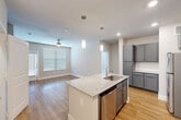 Located at 1720 Summit Crossing Lane in College Station, TX, this single-floor, 2-bedroom, 2-bathroom home offers a well-designed layout with modern finishes throughout. The open-concept kitchen and living area serves as the heart of the home, showcasing warm wood-look flooring, recessed lighting, and a ceiling fan. The kitchen is appointed with granite countertops, a central island with a stainless steel sink, pendant lighting, gray shaker-style cabinetry, a subway tile backsplash, and a full suite of stainless steel appliances including a refrigerator, range, and microwave. The living area benefits from natural light through blinds-fitted windows and flows seamlessly from the kitchen. Both bedrooms feature plush carpet flooring, ceiling fans, and windows that invite natural light. The primary bedroom connects to a private en-suite bathroom with a granite-topped vanity, gray cabinetry, and a tiled soaking tub. Multiple closets — including a spacious walk-in with built-in shelving and hanging rods — provide generous storage throughout. Additional conveniences include a dedicated laundry area and utility room, completing this efficiently designed and thoughtfully appointed home.