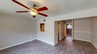 This single-floor residence offers a practical and comfortable layout designed for everyday living. The main living area is bright and open, featuring durable hardwood-style flooring, neutral gray walls, and a ceiling fan with integrated lighting for year-round comfort. A distinctive wall niche adds a subtle architectural detail, while a textured ceiling and recessed ventilation keep the space functional. Natural light filters in through blinds-covered windows, enhancing the airy feel of the room. A front entry door opens directly into this living space, providing convenient access.

The galley-style kitchen is well-equipped, featuring rich dark wood cabinetry, dark granite-look countertops, a double stainless steel sink, and a white coil-burner electric range with an overhead ventilation hood. Hardwood-style flooring continues through the kitchen, and ample upper and lower cabinet storage ensures plenty of room for organization.

The bedrooms are carpeted for warmth and comfort, each offering neutral tones and access to closet space. The primary bedroom benefits from a window with natural views and a dedicated light fixture overhead. Additional bedrooms provide similar carpeted finishes and clean, neutral walls.

The bathroom is clean and functional, featuring a full tub-shower combo with built-in shelving, a toilet, a vanity with wood cabinetry, and hardwood-style flooring throughout.