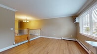 Located at 146 Orchard St in Ellington, Connecticut, this two-floor residence offers a well-organized layout with thoughtfully finished living spaces throughout. The upper floor features warm, light-toned hardwood flooring that runs through the open living and dining areas, accented by elegant crown molding and crisp white baseboards. A chandelier adds a classic touch to the main living space, which is served by baseboard heating and a wall-mounted AC unit for year-round comfort. The kitchen is equipped with rich cherry wood cabinetry, granite countertops, a tile backsplash, stainless steel appliances including a refrigerator, range, microwave, and dishwasher, and a double sink. A staircase with a polished wood banister connects the floors. The lower level includes a generously sized bedroom with plush carpeting, a walk-in closet, and baseboard heating. The full bathroom features a cherry vanity with granite countertop and tile flooring. A window in the bedroom provides a view of the surrounding greenery. The basement level offers a large, open utility or storage area with a painted concrete floor and a small window for natural light, providing practical flexibility for various uses.