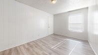 This 590 square foot single-story residence in Killeen, Texas, offers a well-designed living space with modern amenities. The home features two bedrooms, including a primary bedroom of 130 square feet, and one bathroom. The open-concept layout combines the kitchen and living room, maximizing the use of space.

Throughout the home, light wood-look flooring creates a cohesive and contemporary feel. White walls and ceilings enhance the sense of spaciousness and brightness. The kitchen boasts white cabinetry, contrasting black appliances, and a functional layout with ample counter space.

The bathroom features a white tiled tub-shower combination, adding a touch of greenery with a hanging plant. Bedrooms are equipped with ceiling fans and windows with blinds, allowing for natural light and temperature control. The hallway provides access to closet space, indicated by multiple doors.

The property's design prioritizes functionality and modern aesthetics, making efficient use of its compact 590 square foot floor plan. Located at 2908 Lake Rd, Killeen, TX, this home offers a comfortable living space with updated finishes and a clean, contemporary ambiance.