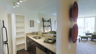 Located at 300 E 17th Ave in Denver's vibrant Capitol Hill neighborhood, this single-floor residence offers a thoughtfully designed living space with modern finishes throughout. The kitchen serves as a focal point of the home, featuring rich dark cabinetry, granite countertops, a stainless steel sink, and a dishwasher. A pass-through opening connects the kitchen seamlessly to the living area, creating an open, connected feel that encourages both functionality and social interaction. The living area is bright and inviting, with natural light filtering through the windows and open shelving that adds both style and practicality. Built-in shelving is also present, providing additional storage and display options. The flooring transitions between wood-style and carpeted surfaces, adding warmth and texture to the space. Neutral wall tones throughout create a calm, versatile backdrop suited to a variety of décor styles. The overall ambiance is contemporary yet comfortable, combining practical design elements with thoughtful details that make the space feel polished and livable. Its central Denver location places residents within easy reach of local dining, entertainment, and urban amenities.