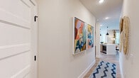 Located in Orlando's Lake Nona area, this 2-bedroom, 2-bathroom residence delivers a well-appointed single-floor layout with contemporary design throughout. The entryway hallway is lined with vibrant wall art and light wood-style flooring that flows seamlessly through the entire home, setting a modern and welcoming tone.

The open-concept kitchen and dining area is a standout feature, boasting two-tone cabinetry — warm natural wood lowers paired with crisp white uppers — complemented by quartz countertops, a subway tile backsplash, stainless steel appliances, and a central island with bar seating illuminated by sleek black pendant lights. This space opens directly into the living area, which is bathed in natural light from multiple windows dressed in bold botanical-print curtains and wood blinds, with a ceiling fan adding comfort overhead.

The primary bedroom is a serene retreat featuring large windows with outdoor views, sheer drapery, and a ceiling fan. The second bedroom is equally bright and well-proportioned. Both bathrooms are clean and modern, with the second bath featuring a soaking tub and shower combination with matte black fixtures. Additional conveniences include two closets, a dedicated laundry space, and a private balcony.