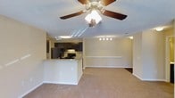 Located at 5300 New Center Dr in Wilmington, North Carolina, this single-floor residence offers a thoughtfully designed open-concept layout that seamlessly connects the kitchen and living areas. The living space features soft, wall-to-wall carpeting and neutral-toned walls that create a warm and inviting atmosphere. A ceiling fan with integrated lighting anchors the living area, providing both comfort and illumination.

The kitchen is a standout feature, showcasing dark cabinetry that contrasts elegantly with the granite-style countertops. A peninsula with a breakfast bar extends into the living space, offering additional seating and a natural division between the two areas. The kitchen is equipped with black appliances, including a refrigerator and range, and benefits from dedicated overhead lighting that highlights the workspace. A textured ceiling throughout adds subtle visual character to the interior.

Track lighting in the dining area provides focused illumination, making the space equally functional for everyday meals or entertaining. The clean lines, cohesive color palette, and efficient use of space make this residence a practical and comfortable home. Its single-floor design ensures easy accessibility and a smooth flow throughout the living areas.