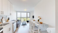 Located at 333 University Avenue in Kingston, Ontario, this modern 4-bedroom, 1-bathroom unit offers a thoughtfully designed layout across a single floor. The open-concept living and dining area is a standout feature, anchored by expansive floor-to-ceiling windows that flood the space with natural light and frame sweeping panoramic views of Kingston's cityscape and surrounding greenery. Light wood laminate flooring runs throughout, complementing the clean white walls and contemporary aesthetic.

The kitchen is sleek and functional, outfitted with white cabinetry, light countertops, a subway tile backsplash, and stainless steel appliances including a range, over-the-range microwave, and dishwasher. The living area connects seamlessly to the dining space, creating an open, airy feel ideal for shared living.

Each of the four bedrooms maintains the unit's bright, minimal character, with white walls, wood flooring, and built-in closets. Several bedrooms benefit from large windows with city views, making them well-suited as both sleeping and study spaces. The primary bedroom offers a generous footprint with ample closet storage.

The bathroom is clean and modern, featuring a glass-enclosed corner shower, white tile surround, a vanity with under-sink storage, and neutral tile flooring. A bright hallway connects all rooms efficiently, completing this well-organized and light-filled space.