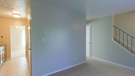 This two-floor residential space offers a straightforward and functional layout with a calm, neutral aesthetic throughout. The interior is finished with soft wall-to-wall carpeting that adds warmth underfoot and contributes to the quiet, understated character of the home. Walls are painted in light, muted tones — as seen in the image, a cool grey-blue palette provides a clean and versatile backdrop that adapts well to a variety of furnishing styles. White baseboards and trim offer a crisp contrast against the neutral walls, lending a tidy and well-maintained appearance to the rooms. The interior doors feature a simple, classic panel design with gold-toned hardware, consistent with the space's clean and unpretentious style. The textured ceilings add a subtle dimensional quality overhead. Spread across two floors, the layout provides a natural separation between living and private areas, offering both communal and personal spaces within the home. The overall ambiance is calm and move-in ready, suited for those seeking a clean, low-key living environment with a practical and cohesive design throughout.