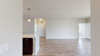 Located at 2200 Seasons Blvd in Dundee, Illinois, this single-floor residence offers a clean, modern design with an open-concept layout that promotes a bright and airy atmosphere throughout. The living area features light wood-tone flooring and large glass doors that invite natural light and provide outdoor views, creating a seamless connection between interior and exterior spaces.

The kitchen is a standout feature, showcasing rich dark espresso cabinetry paired with light quartz countertops and a generous island with a built-in sink. Stainless steel appliances, including a refrigerator, electric range, and microwave, complete the well-equipped space. Pendant lighting above the island adds a refined touch, while the layout flows naturally into the open living area.

The bedroom includes soft neutral carpet, ample closet space with built-in shelving, and easy access to adjoining rooms. Two bathrooms serve the residence — one featuring a glass-enclosed walk-in shower with wood-toned vanity cabinetry, and a second with a full soaking tub and shower combination. Both bathrooms are finished with light wood-look flooring and dark wood vanities for a cohesive aesthetic.

A dedicated in-unit laundry area houses a full-size front-loading washer and dryer, adding everyday convenience. Neutral tones and consistent finishes throughout give this residence a polished, move-in-ready appeal.