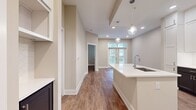 This 620 square foot apartment offers a thoughtful blend of style and functionality. The heart of the home is a sleek, modern kitchen that maximizes space efficiency. White cabinetry extends to the ceiling, providing abundant storage, while glass-front upper cabinets add visual interest. Stainless steel appliances, including a built-in microwave and full-size refrigerator, offer contemporary convenience. The kitchen's centerpiece is a generously sized island with a white quartz countertop, perfect for meal prep or casual dining.

The open-concept layout creates a seamless flow between the kitchen and living areas, making the space feel larger and more cohesive. Recessed lighting and pendant fixtures over the island ensure the space is well-lit. The warm wood-look flooring throughout adds warmth and durability.

With one bedroom (160 sq ft) and one bathroom, this apartment is ideal for singles or couples. A closet provides additional storage. The neutral color palette and clean lines create a canvas for personal style, while the overall design suggests a modern, urban aesthetic. Despite its compact size, this apartment offers a comfortable and efficient living space with attention to detail in its finishes and layout.