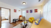 This efficiently designed 2-bedroom, 1-bathroom single-floor unit offers a practical and well-organized layout across its rooms. The living room serves as the central gathering space, featuring warm hardwood flooring, multiple windows that allow natural light to fill the area, and enough room for comfortable seating arrangements. The galley-style kitchen is lined with warm oak cabinetry on both sides, providing ample storage, and is equipped with a full suite of appliances including a refrigerator, electric range, dishwasher, and microwave — all set over easy-care tile flooring. The primary bedroom offers a cozy and functional footprint with hardwood flooring, a window for natural light, and sufficient space for a bed and storage. The second bedroom, similar in design, also features hardwood flooring and a window, making it suitable as a sleeping space or flexible-use room. The shared bathroom is fitted with warm wood-toned cabinetry, a single vanity, and a shower/tub combination with tile flooring. Throughout the unit, neutral wall tones and consistent wood-accented finishes create a cohesive and functional living environment well-suited for roommates or small households.