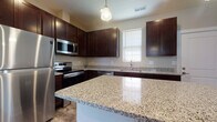 Located at 1733 Bellmeadow Dr in Lancaster, Ohio, this two-floor home offers a well-designed layout with modern finishes and functional living spaces across both levels. The kitchen is a standout feature, showcasing rich dark cabinetry, polished granite countertops, and a full suite of stainless steel appliances including a refrigerator, electric range, over-the-range microwave, and dishwasher. A large central island with matching granite provides additional prep space and casual seating, while a pendant light above adds a refined touch. Wood-look flooring runs through the main living areas on the first floor, complementing the neutral wall tones and creating a warm, cohesive aesthetic. A convenient half bath is also found on the main level. Upstairs, carpeted bedrooms offer a comfortable retreat, with multiple windows allowing generous natural light and views of the surrounding neighborhood. The upper-level bathroom is well-appointed with a walk-in glass-enclosed shower, granite-topped vanity with dark cabinetry, and tile flooring. Throughout the home, clean white trim, panel doors, and a consistent neutral color palette contribute to a fresh, move-in-ready atmosphere that suits a variety of personal styles.