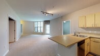 Located at 920 NW 12th Ave in Portland's vibrant Pearl District, this single-floor unit offers a well-designed open-concept layout that promotes a sense of spaciousness throughout. The living area is finished with neutral-toned carpet and painted in soft, warm hues, creating an inviting atmosphere. Large windows allow natural light to fill the space, and a glass door provides direct access to a private balcony, enhancing the connection to the outdoors. A wall-mounted HVAC unit and track lighting overhead add functional, modern touches to the living area.

The kitchen is positioned at the open end of the living space, anchored by a peninsula with granite-style countertops that also serves as a breakfast bar. Light maple cabinetry pairs with stainless steel appliances, including a range, over-the-range microwave, and refrigerator, while wood-style flooring grounds the culinary space with a warm contrast.

The bedroom is carpeted and well-proportioned, featuring a ceiling fan, a window with blinds, and ample wall space. Two bathrooms each include a tub/shower combination, granite-style vanity countertops, light wood cabinetry, tile flooring, and brushed nickel fixtures and grab bars throughout.