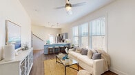 Located at 267 Grand Cypress Rd in Summerville, SC, this two-story home offers a well-designed layout with thoughtful finishes throughout. The main floor centers on an open-concept living area distinguished by soaring vaulted ceilings and large windows that flood the space with natural light. Durable hardwood-style flooring runs throughout, anchoring a bright and welcoming atmosphere. A ceiling fan adds both style and function to the generous living space.

The kitchen is a standout feature, equipped with stainless steel appliances, gray cabinetry, a white countertop peninsula with seating for multiple bar stools, and elegant pendant lighting overhead — making it ideal for both everyday meals and entertaining. The main entrance is welcoming, with a transom window above the front door that brings in additional light.

The bedrooms are calm and neutral in tone, each featuring hardwood-style floors, ceiling fans or track lighting, and access to natural light. One bedroom includes direct access to a private balcony. The primary bathroom is well-appointed with a double vanity featuring gray cabinetry, white countertops, a glass-enclosed shower, and wood-look flooring. A dedicated laundry room with full-size washer and dryer hookups and shelving adds practical convenience to the home.