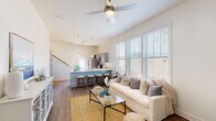 Located at 267 Grand Cypress Rd in Summerville, SC, this two-story home offers a well-designed layout with thoughtful finishes throughout. The main floor centers on an open-concept living area distinguished by soaring vaulted ceilings and large windows that flood the space with natural light. Durable hardwood-style flooring runs throughout, anchoring a bright and welcoming atmosphere. A ceiling fan adds both style and function to the generous living space.

The kitchen is a standout feature, equipped with stainless steel appliances, gray cabinetry, a white countertop peninsula with seating for multiple bar stools, and elegant pendant lighting overhead — making it ideal for both everyday meals and entertaining. The main entrance is welcoming, with a transom window above the front door that brings in additional light.

The bedrooms are calm and neutral in tone, each featuring hardwood-style floors, ceiling fans or track lighting, and access to natural light. One bedroom includes direct access to a private balcony. The primary bathroom is well-appointed with a double vanity featuring gray cabinetry, white countertops, a glass-enclosed shower, and wood-look flooring. A dedicated laundry room with full-size washer and dryer hookups and shelving adds practical convenience to the home.