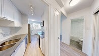 Located on the 8th floor at 250 Roehampton Avenue in Toronto's midtown neighbourhood, this thoughtfully designed suite offers a clean, modern aesthetic throughout its single-floor layout. The galley-style kitchen is a functional highlight, featuring white cabinetry, subway tile backsplash, dark countertops, stainless steel appliances including a built-in microwave, electric range, and dishwasher, all set above warm light wood-toned flooring. Recessed track lighting illuminates the kitchen corridor, which connects efficiently to the rest of the unit. The living area is bright and airy, benefiting from a window that frames views of the surrounding cityscape, with a baseboard heating unit running along the exterior wall. The bedroom is a clean, neutrally finished space with the same light hardwood-style flooring and crisp white walls, offering a calm and versatile environment. The bathroom is finished to a high standard, showcasing classic white subway tile surrounding a full soaker tub with an overhead shower, complemented by stone-look floor tiles and a clean white vanity. Throughout the unit, consistent use of white walls, light flooring, and modern fixtures creates a cohesive, bright, and contemporary living environment.