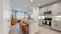 This thoughtfully designed one-bedroom, one-bathroom residence offers a bright and cohesive living environment with modern finishes throughout. The open-concept kitchen and living area serves as the heart of the home, anchored by a central island with granite countertops, an undermount sink, and bar seating — ideal for both casual dining and entertaining. The kitchen is fully equipped with stainless steel appliances, including a French door refrigerator, electric range, microwave, and dishwasher, complemented by sage-toned cabinetry and a classic white subway tile backsplash. Light wood-style flooring flows seamlessly throughout the entire unit, enhancing the airy, cohesive aesthetic. The living room features a ceiling fan, large window with natural light, and ample space for relaxing. The bedroom is a comfortable retreat with its own ceiling fan, a generous window framing greenery views, and access to a spacious walk-in closet outfitted with wire shelving and hanging rods. The bathroom is well-appointed with a granite-topped vanity, wood-toned cabinetry, large-format tile surrounding the tub and shower, and consistent light flooring. A dedicated entrance completes this efficiently laid-out, move-in-ready home.