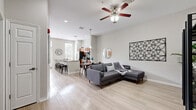 This single-floor, 2-bedroom, 1-bathroom residence offers a thoughtfully designed open-concept layout that seamlessly connects the living, dining, and kitchen areas. Light wood-style flooring flows throughout the space, complementing the neutral gray-toned walls and creating a bright, cohesive aesthetic.

The living area is generously proportioned, featuring a ceiling fan and ample room for relaxed seating. It flows naturally into the dining space, which is anchored by a pendant light, and further into the kitchen. The kitchen is a standout feature, boasting rich wood cabinetry, granite countertops, stainless steel appliances, and a large island with bar seating. Tall windows and French doors allow abundant natural light to pour in, enhancing the kitchen's airy feel.

The primary bedroom offers a comfortable, well-scaled retreat, while the second bedroom features matching light flooring and a ceiling fan. Both rooms are finished with the same neutral palette found throughout the home. The bathroom is clean and functional, featuring light wood-look flooring, a sleek vanity with warm wood cabinetry, a white countertop, and a tiled walk-in shower with a glass sliding door.

The entryway provides a welcoming transition into the home, with generous wall space and clear sightlines down the hallway to the bedrooms, reinforcing the open and connected feel of the entire residence.