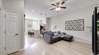 This single-floor, 2-bedroom, 1-bathroom residence offers a thoughtfully designed open-concept layout that seamlessly connects the living, dining, and kitchen areas. Light wood-style flooring flows throughout the space, complementing the neutral gray-toned walls and creating a bright, cohesive aesthetic.

The living area is generously proportioned, featuring a ceiling fan and ample room for relaxed seating. It flows naturally into the dining space, which is anchored by a pendant light, and further into the kitchen. The kitchen is a standout feature, boasting rich wood cabinetry, granite countertops, stainless steel appliances, and a large island with bar seating. Tall windows and French doors allow abundant natural light to pour in, enhancing the kitchen's airy feel.

The primary bedroom offers a comfortable, well-scaled retreat, while the second bedroom features matching light flooring and a ceiling fan. Both rooms are finished with the same neutral palette found throughout the home. The bathroom is clean and functional, featuring light wood-look flooring, a sleek vanity with warm wood cabinetry, a white countertop, and a tiled walk-in shower with a glass sliding door.

The entryway provides a welcoming transition into the home, with generous wall space and clear sightlines down the hallway to the bedrooms, reinforcing the open and connected feel of the entire residence.