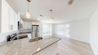 Located at 1418 Frontier Valley Dr in Austin, TX, this 2-bedroom, 1-bathroom residence offers a clean, modern aesthetic with a well-planned single-floor layout. Light wood flooring runs throughout, creating a cohesive and airy feel across the entire space.

The open-concept kitchen serves as the heart of the home, featuring white shaker cabinetry, granite countertops, a subway tile backsplash, and a peninsula with an undermount sink. Stainless steel appliances — including a refrigerator, range, and microwave — add a polished, contemporary touch. Pendant lighting above the peninsula and abundant natural light from large windows enhance the kitchen's bright, functional character.

The living area flows naturally from the kitchen, bathed in natural light through floor-to-ceiling vertical blinds that lead to an outdoor view. Both bedrooms are well-proportioned, each equipped with a ceiling fan, light-filtering window blinds offering outdoor views, and a dedicated closet with built-in hanging rods and sliding doors. The primary bedroom offers a comfortable footprint with dual windows.

The bathroom is finished with classic white subway tile surrounding a full soaking tub and shower, brushed nickel fixtures, and light wood-tone flooring. Throughout the residence, a neutral color palette and modern finishes create a clean, inviting atmosphere ideal for everyday living.