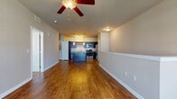 Located at 5900 Wilkinson Rd in Sarasota, Florida, this single-floor residence offers a well-appointed, open-concept layout designed for comfortable everyday living. The main living area is expansive and airy, featuring warm hardwood-style flooring, neutral toned walls, and a ceiling fan that enhances the bright, inviting atmosphere. A half-wall partition elegantly defines the living space while maintaining an open visual connection throughout the floor plan.

The kitchen is a standout feature, showcasing rich dark cabinetry, gleaming granite countertops, and a large central island ideal for meal prep or casual dining. Stainless steel appliances — including a range, microwave, and dishwasher — are complemented by pendant lighting and a distinctive built-in wine rack, adding a refined touch to the space.

The bedrooms are carpeted for comfort and receive generous natural light through large windows fitted with blinds, offering both brightness and privacy. The bathroom is clean and functional, featuring hardwood-style flooring, a tub-shower combination with tiled surround, and a dark vanity with granite countertops that echoes the kitchen's design aesthetic.

A carpeted staircase with a handrail provides access between levels of the building. Throughout, the space maintains a cohesive, modern design with consistent finishes and a neutral color palette suited to a variety of décor styles.
