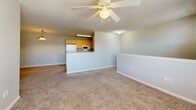 Located at 13900 S Peoria Ave in Glenpool, Oklahoma, this one-bedroom, one-bathroom unit offers a functional and well-organized layout across a single floor. The open living area is finished with plush carpeting and features a ceiling fan with light, creating a comfortable and airy atmosphere. A pass-through counter connects the living space to the kitchen, which is equipped with light wood cabinetry, a refrigerator, microwave, and electric range — providing an efficient cooking area with direct sightlines to the main living space. The bedroom is generously sized, featuring soft carpeting, a ceiling fan, a natural light-providing window with blinds, and a double-door closet offering ample storage. A hallway connects the main areas and leads to the full bathroom, which includes a wood-toned vanity with a sink and dark countertop, a large mirror, and tile flooring. A staircase is also present within the unit, adding a distinctive architectural element to the space. The textured ceilings and neutral wall tones throughout give the unit a clean, cohesive look, making it a practical and comfortable home in Glenpool, OK.