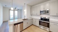 Located at 2600 Lakefront Trail in Rockwall, TX, this one-bedroom, one-bathroom residence offers a well-designed single-floor layout with a clean, modern aesthetic. The open-concept living area seamlessly integrates the kitchen, dining, and living spaces, creating an inviting and functional environment. The kitchen is a standout feature, equipped with stainless steel appliances including a refrigerator, electric range, microwave, and dishwasher. White shaker-style cabinetry with brushed nickel hardware pairs elegantly with granite countertops and a decorative patterned tile backsplash. A peninsula with an undermount sink provides additional prep space and casual seating potential. Light wood-style flooring runs throughout the main living areas, while pendant lighting adds a polished touch overhead. The bedroom is a comfortable retreat finished with plush carpet, a ceiling fan, and a window that fills the room with natural light. The bathroom features wood-look tile flooring, a soaking tub with white subway tile surround, a granite-topped vanity, and convenient access to a dedicated walk-in closet with built-in shelving. Two closets total provide ample storage. A private patio extends the living space outdoors, ideal for relaxing or taking in the surroundings.