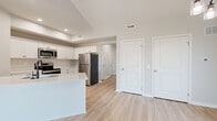 Located at 251 Carlson Lane in Macedon, NY, this single-floor residence offers a thoughtfully arranged two-bedroom, one-bathroom layout with contemporary finishes and a clean, neutral aesthetic throughout. Light-toned luxury vinyl plank flooring runs through the main living areas, complementing the bright, airy atmosphere created by the soft gray and white color palette.

The open-concept kitchen and living room form the heart of the home. The kitchen features crisp white shaker-style cabinetry with matte black hardware, white countertops, a peninsula with an integrated sink, and a full suite of stainless steel appliances, including a refrigerator, electric range, built-in microwave, and dishwasher. Recessed lighting highlights the space, which flows seamlessly into the spacious living area. A large sliding glass door floods the living room with natural light and provides outdoor access.

Both bedrooms are finished with plush carpet and offer ample natural light through double windows. The primary bedroom features vaulted ceilings, adding a sense of volume. The second bedroom includes a walk-in closet. The full bathroom is finished with light flooring, a dark-stained vanity, white countertop, and accessible grab bars. Three hallways connect the rooms efficiently, rounding out this well-organized home.