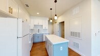This two-story, 2-bedroom, 1.5-bathroom home in Port Arthur, TX offers a thoughtfully designed layout spread across two floors. The main level hosts the living room, kitchen, pantry, and a half bath, while the upper level is dedicated to the two bedrooms and a full bathroom.

The kitchen is a standout feature, showcasing light blue lower cabinetry paired with crisp white upper cabinets, gold hardware accents, a geometric patterned tile backsplash, and a white quartz-topped center island illuminated by stylish pendant lights. White appliances and warm wood-look flooring complete the clean, modern aesthetic. An adjacent pantry provides convenient additional storage.

Both bedrooms are located on the upper floor and share a consistent design language — neutral white walls, warm wood-look flooring, ceiling fans, and windows that bring in natural light. Each bedroom includes closet space, with the second bedroom featuring a double-door closet.

The full bathroom is finished with vertical white subway tile surrounding the tub/shower combo, a white vanity with brushed nickel fixtures, and a large mirror, creating a bright and clean environment.

The consistent use of warm wood-look flooring, neutral tones, and modern fixtures throughout both floors gives the home a cohesive and contemporary feel.