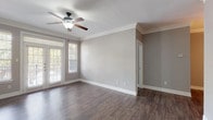 This single-story, 2-bedroom, 2-bathroom residence offers a thoughtfully designed layout with consistent dark hardwood-style flooring and neutral gray walls throughout. Crown molding accents every room, adding a refined architectural detail that elevates the overall aesthetic.

The living area is generously sized, featuring a ceiling fan, French doors that invite natural light and outdoor views, and a built-in shelving and cabinet unit that provides both storage and a distinctive focal point. A pendant light marks the adjacent dining area, which flows naturally toward the kitchen.

The galley-style kitchen is well-equipped with dark cabinetry, dark granite countertops, stainless steel appliances including an electric range, microwave, refrigerator, and dishwasher, and wood-style flooring that ties the space together cohesively.

Each bedroom is comfortably proportioned, featuring ceiling fans, crown molding, and windows that bring in natural light. The primary bathroom includes a dual-sink vanity with a wide mirror, dark cabinetry, and white countertops. The second bathroom offers a full tub-shower combination. A dedicated laundry room with a full-size washer and dryer completes this functional and well-finished residence.