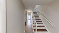 Located at 2106 Front St in Durham, NC, this two-story home offers a well-organized layout across two floors with a clean, neutral aesthetic throughout. The entryway greets visitors with light hardwood-style flooring and a striking staircase featuring dark wood treads and a white balustrade, setting the tone for the rest of the home.

The main living area is bright and open, with hardwood-style flooring, a ceiling fan with integrated lighting, and access to an exterior door that allows natural light to fill the space. The kitchen is a standout feature, equipped with crisp white shaker-style cabinetry, stainless steel appliances including a range, dishwasher, and microwave, complemented by a tasteful mosaic tile backsplash and a window above the sink.

Bedrooms are carpeted for comfort and feature neutral walls, natural light from windows with blinds, and mirrored sliding-door closets offering ample storage. The bathrooms are functional and well-appointed, with a tub/shower combination, a grab bar for added safety, a white vanity, and wood-look tile flooring. Textured ceilings are consistent throughout the home, adding a classic residential character to every room.